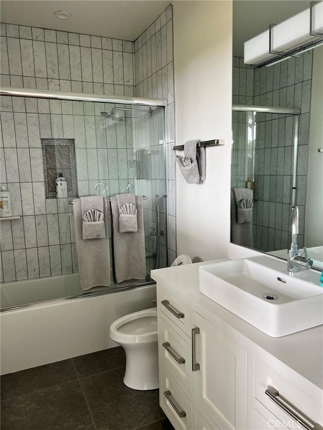 bathroom with tile patterned floors, combined bath / shower with glass door, toilet, and vanity