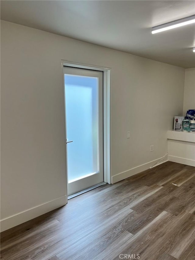 spare room featuring baseboards and wood finished floors