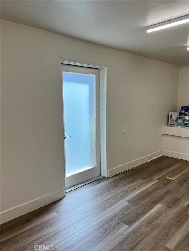 spare room with baseboards and wood finished floors