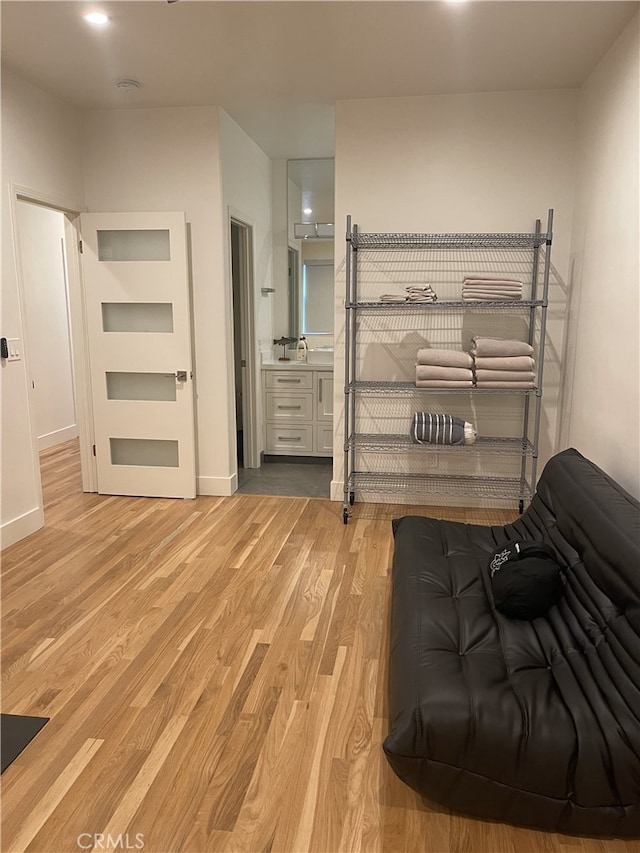 bedroom with light wood-type flooring, baseboards, and connected bathroom