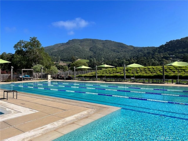 pool with a mountain view, a patio area, and fence