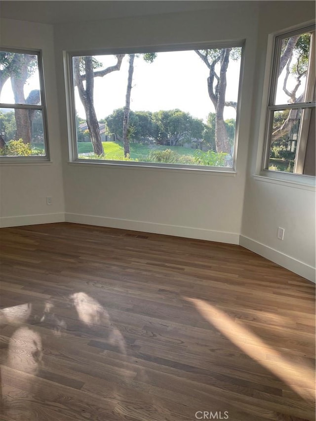 unfurnished room with baseboards and dark wood-style flooring