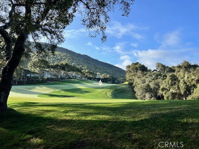 view of home's community with a mountain view, a yard, and golf course view