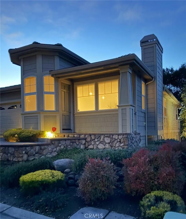 exterior space featuring stone siding and a chimney