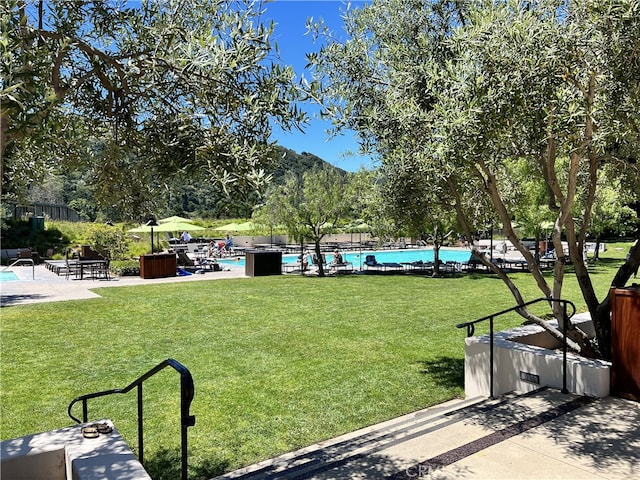 surrounding community with a lawn, a swimming pool, and a patio area