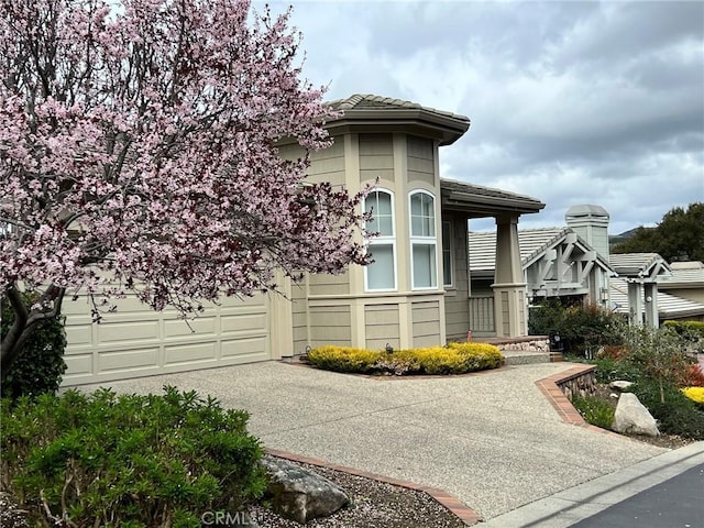 view of property exterior with concrete driveway, a tiled roof, and a garage