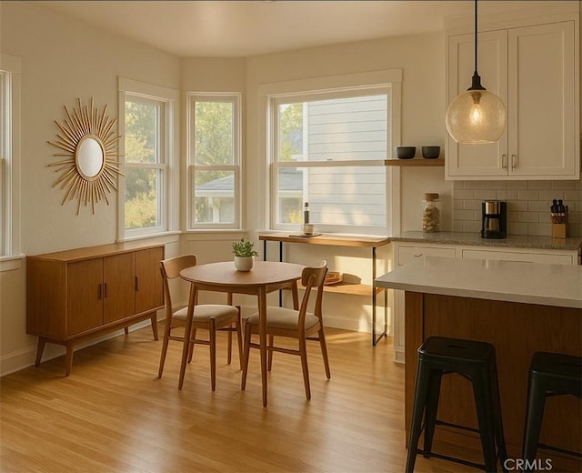 dining space with baseboards, a healthy amount of sunlight, and light wood-style flooring