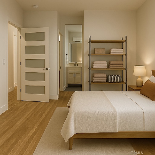 bedroom featuring baseboards, a sink, connected bathroom, and wood finished floors