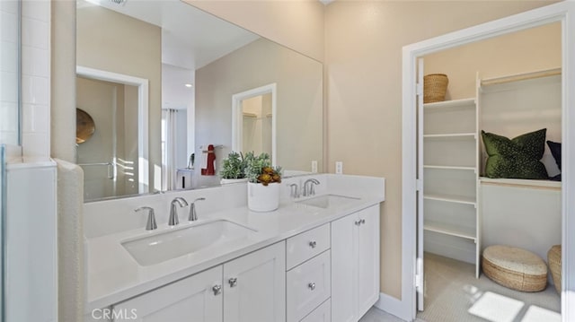 bathroom featuring a sink, a spacious closet, and double vanity