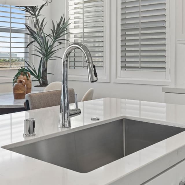 interior details featuring a sink, white cabinets, and light countertops