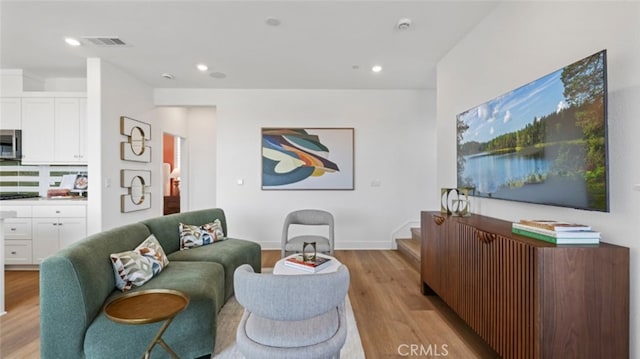 living room with recessed lighting, visible vents, light wood finished floors, and baseboards