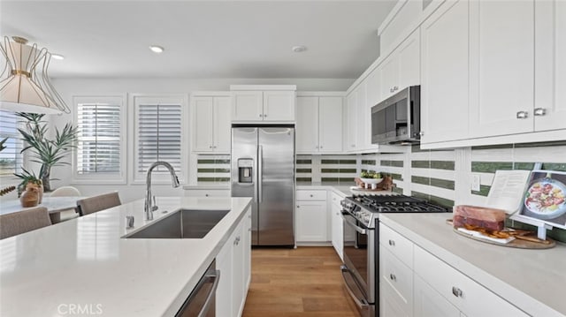 kitchen with a sink, appliances with stainless steel finishes, white cabinets, and light countertops