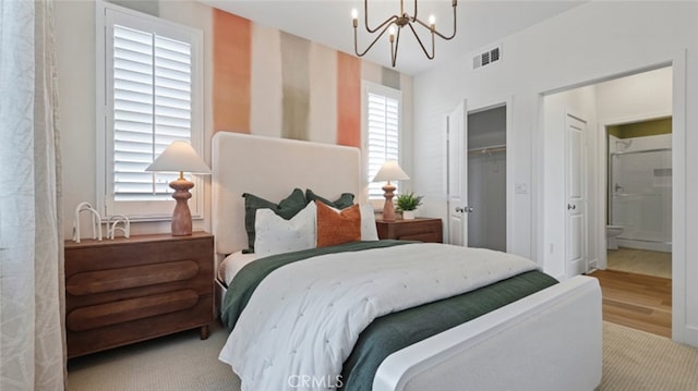 bedroom with visible vents, ensuite bath, a closet, and a chandelier