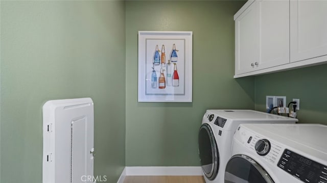 washroom featuring washer and clothes dryer, cabinet space, baseboards, and wood finished floors