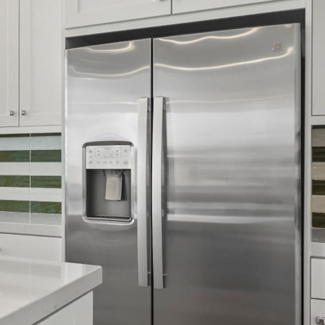 room details featuring light countertops, stainless steel refrigerator with ice dispenser, and white cabinetry