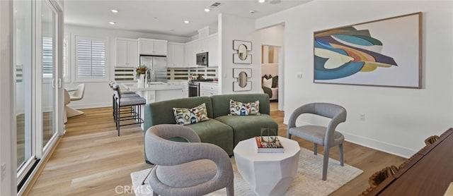 living room with visible vents, recessed lighting, baseboards, and light wood finished floors