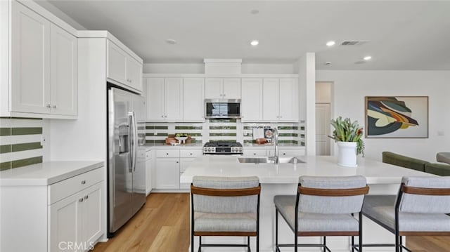 kitchen featuring visible vents, a breakfast bar area, stainless steel appliances, and a sink