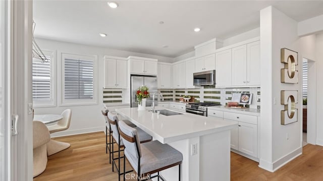 kitchen with a sink, a kitchen breakfast bar, white cabinetry, and stainless steel appliances