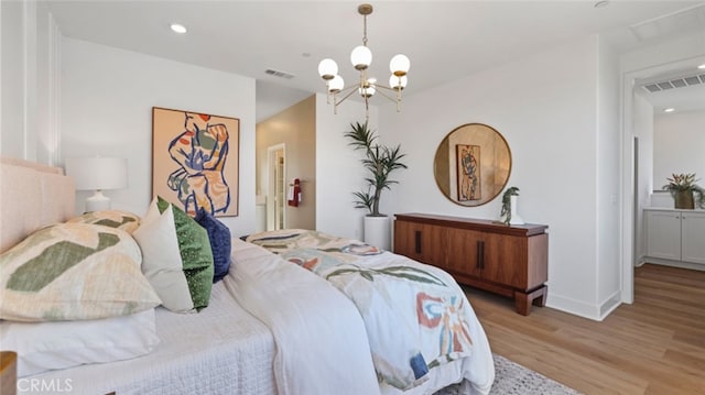 bedroom with a chandelier, visible vents, light wood-style flooring, and baseboards