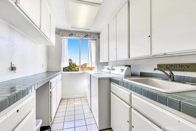 laundry area with baseboards, light tile patterned flooring, cabinet space, independent washer and dryer, and a sink