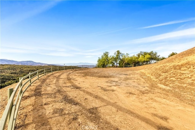 view of yard featuring a mountain view, a rural view, and fence