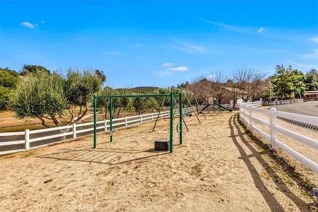 view of property's community with a rural view, fence, and playground community