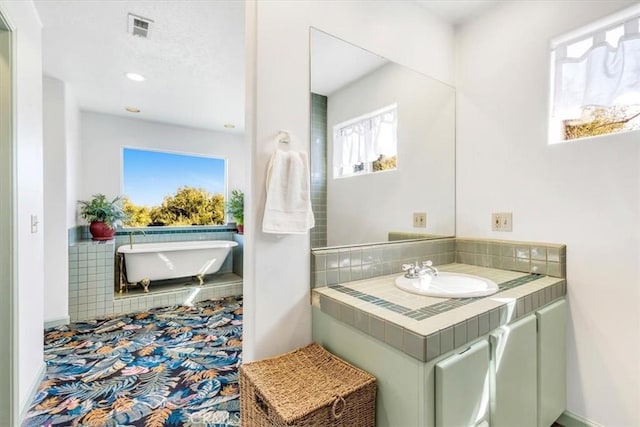 full bath with visible vents, a soaking tub, and vanity