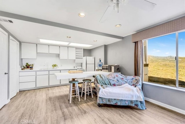 bedroom featuring visible vents, light wood-type flooring, freestanding refrigerator, and baseboards