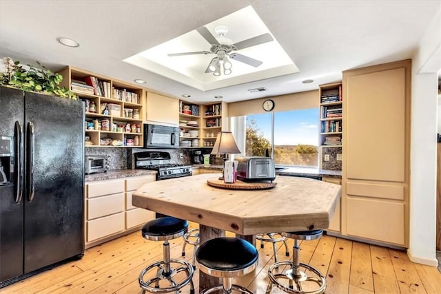 kitchen with visible vents, a tray ceiling, light wood-style flooring, open shelves, and black appliances