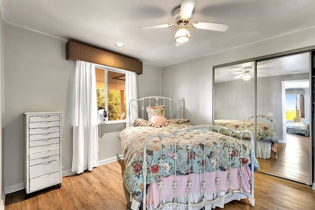 bedroom featuring a closet, baseboards, wood finished floors, and a ceiling fan