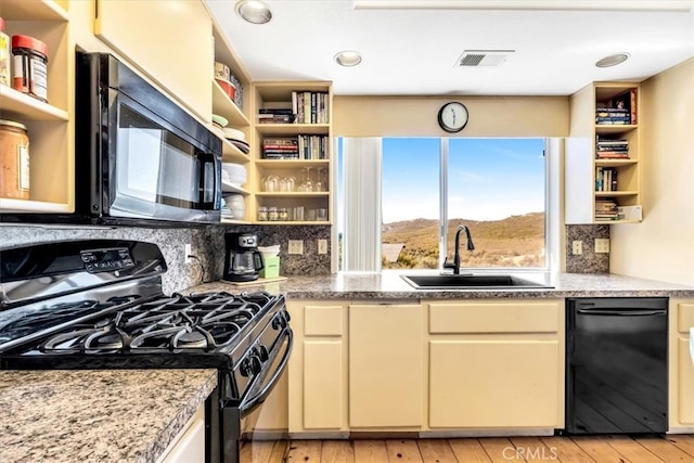 kitchen with visible vents, open shelves, a sink, black appliances, and cream cabinets