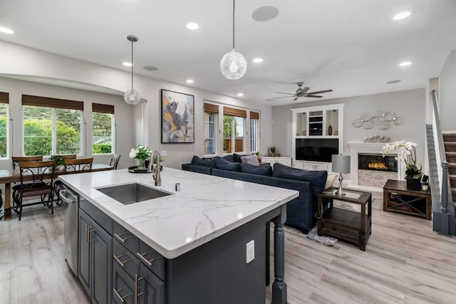 kitchen featuring a sink, a glass covered fireplace, recessed lighting, light wood finished floors, and dishwasher