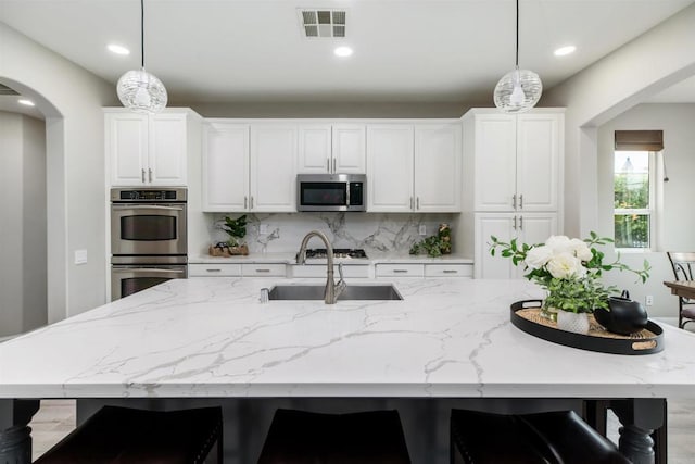 kitchen with visible vents, pendant lighting, tasteful backsplash, stainless steel appliances, and arched walkways