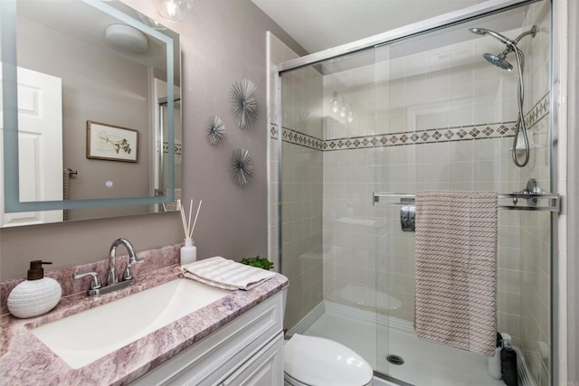 bathroom featuring vanity, a shower stall, and toilet