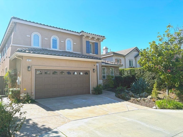 mediterranean / spanish-style home with a tiled roof, driveway, and stucco siding