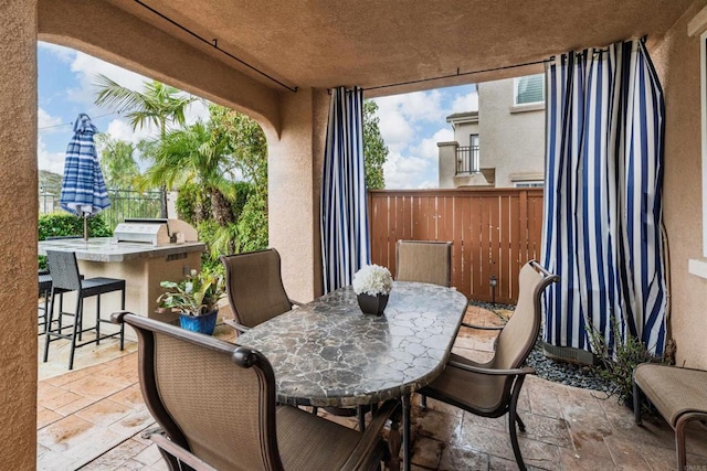 view of patio / terrace with fence, outdoor wet bar, a grill, exterior kitchen, and outdoor dining area