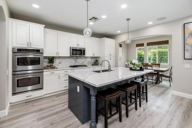 kitchen featuring visible vents, a sink, backsplash, white cabinetry, and appliances with stainless steel finishes