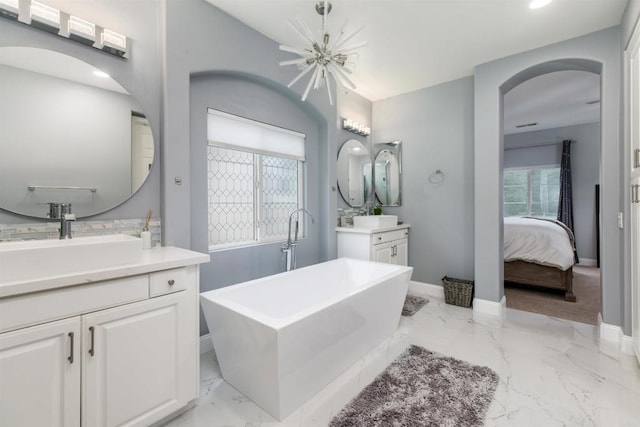 ensuite bathroom with marble finish floor, a sink, ensuite bath, baseboards, and a freestanding bath