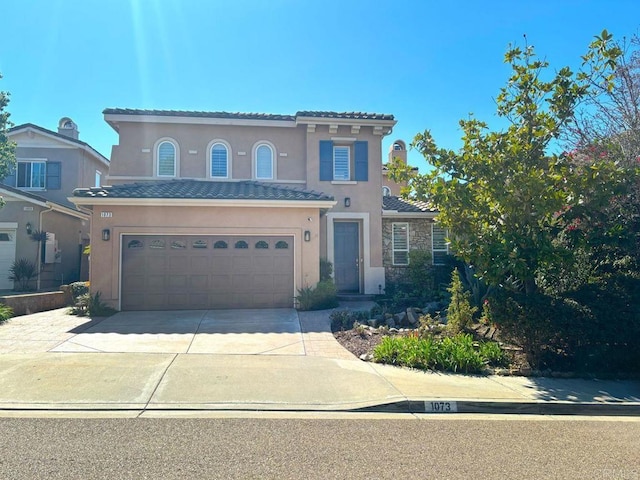 mediterranean / spanish home featuring stucco siding, an attached garage, driveway, and a tiled roof