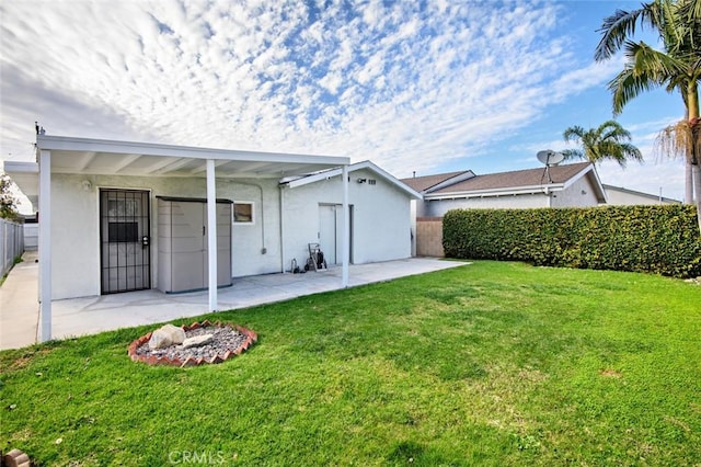 back of house with stucco siding, a lawn, a patio area, and fence