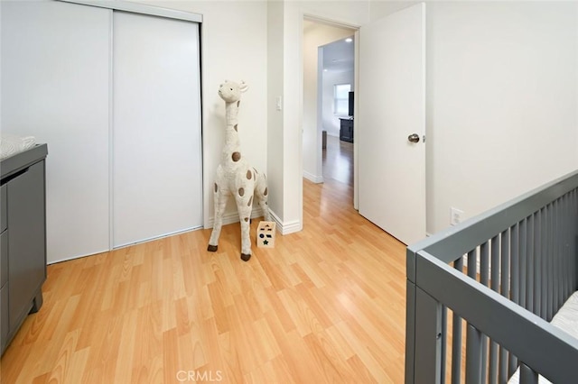 bedroom with a closet, baseboards, and light wood finished floors