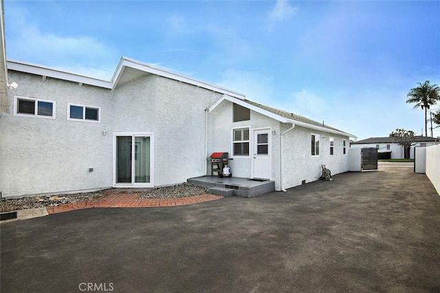 rear view of property featuring a patio area, stucco siding, and fence