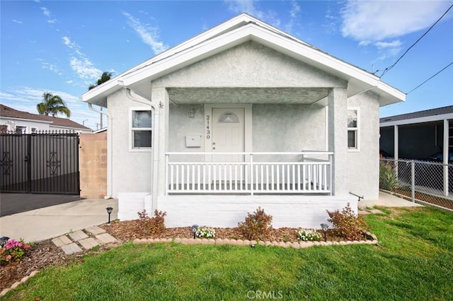 bungalow-style house with stucco siding, a porch, a front lawn, and fence