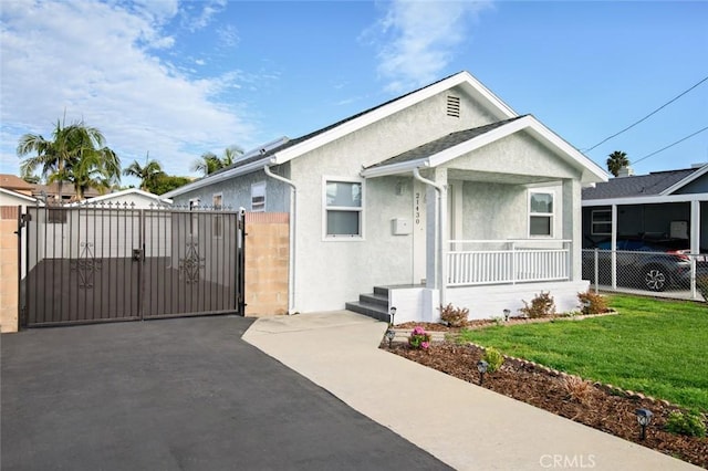 bungalow with stucco siding, fence, a front lawn, and a gate