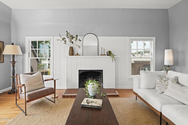 living room featuring a wealth of natural light, a fireplace with raised hearth, and wood finished floors