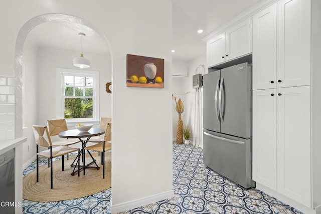 kitchen with freestanding refrigerator, recessed lighting, arched walkways, white cabinets, and light countertops