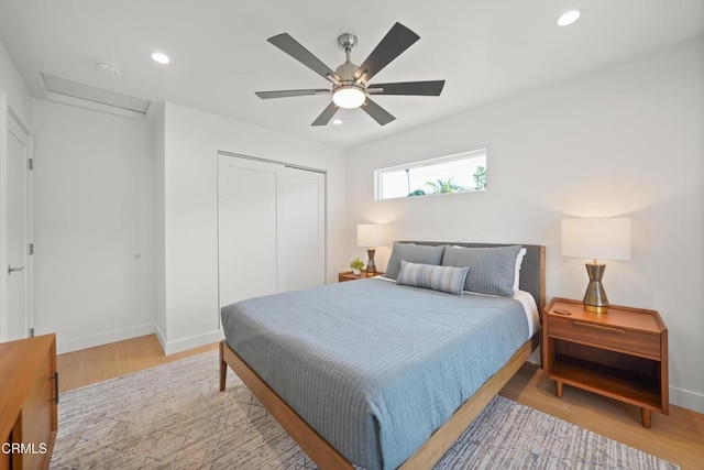 bedroom with a closet, recessed lighting, attic access, and light wood-style floors