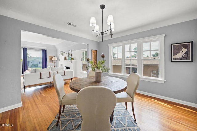 dining room featuring visible vents, a healthy amount of sunlight, baseboards, and wood finished floors