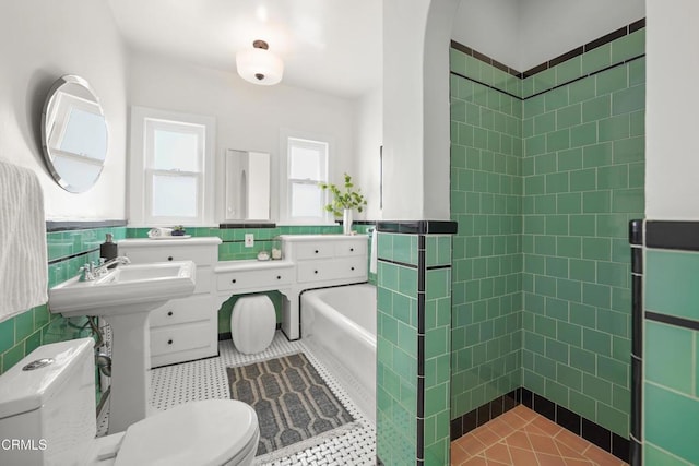 bathroom with toilet, tile walls, wainscoting, and a tile shower