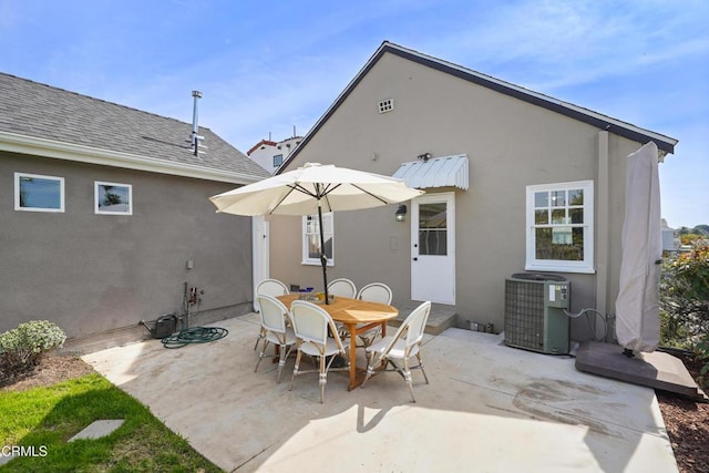 back of property featuring stucco siding, roof with shingles, outdoor dining area, central AC unit, and a patio area